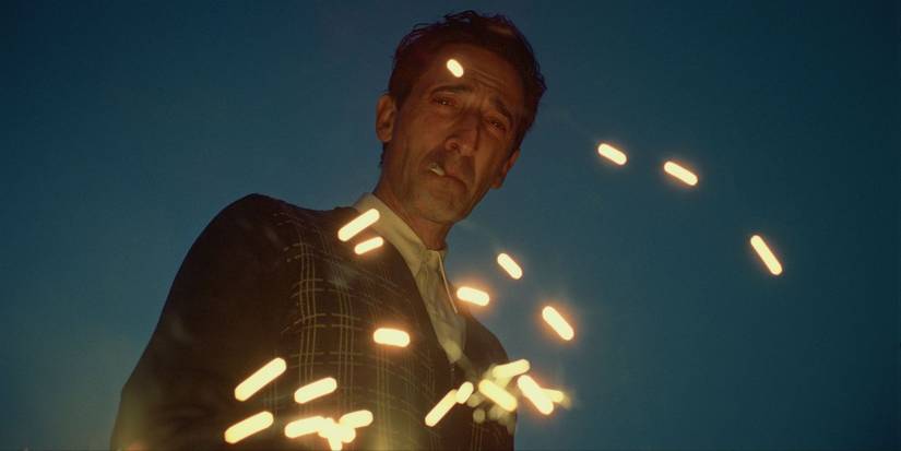 Sparks flying around Adrien Brody as László Tóth with a cigarette in his mouth in The Brutalist.