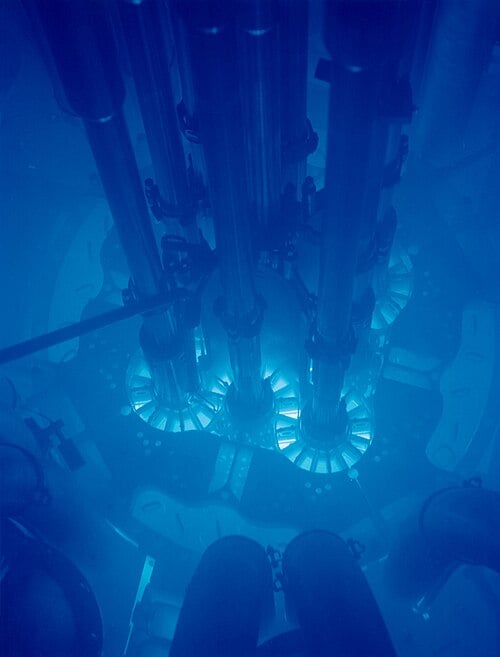 The Advanced Test Reactor at Idaho National Laboratory — the blue glow is Cherenkov radiation from electrons outracing light in water. Argonne National Laboratory. CC BY-SA 2.0, via Wikimedia Commons.