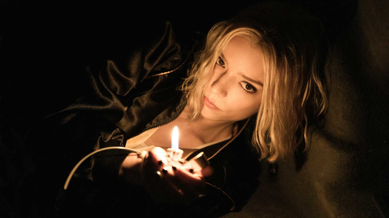 Anya Taylor-Joy holding a lighter in a dark space in Lucky