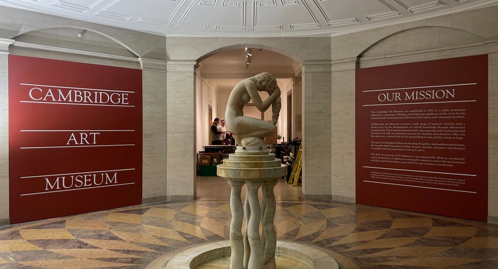 Interior of the Cambridge Art Museum featuring a sculpture of a woman and informative wall texts.