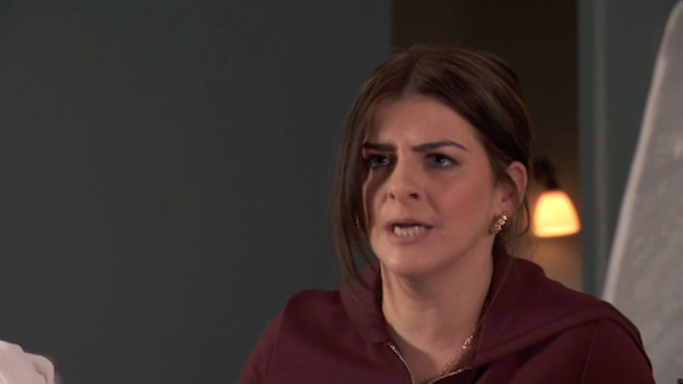 hollyoaks beth keane woman with obscured face wearing a maroon sweatshirt