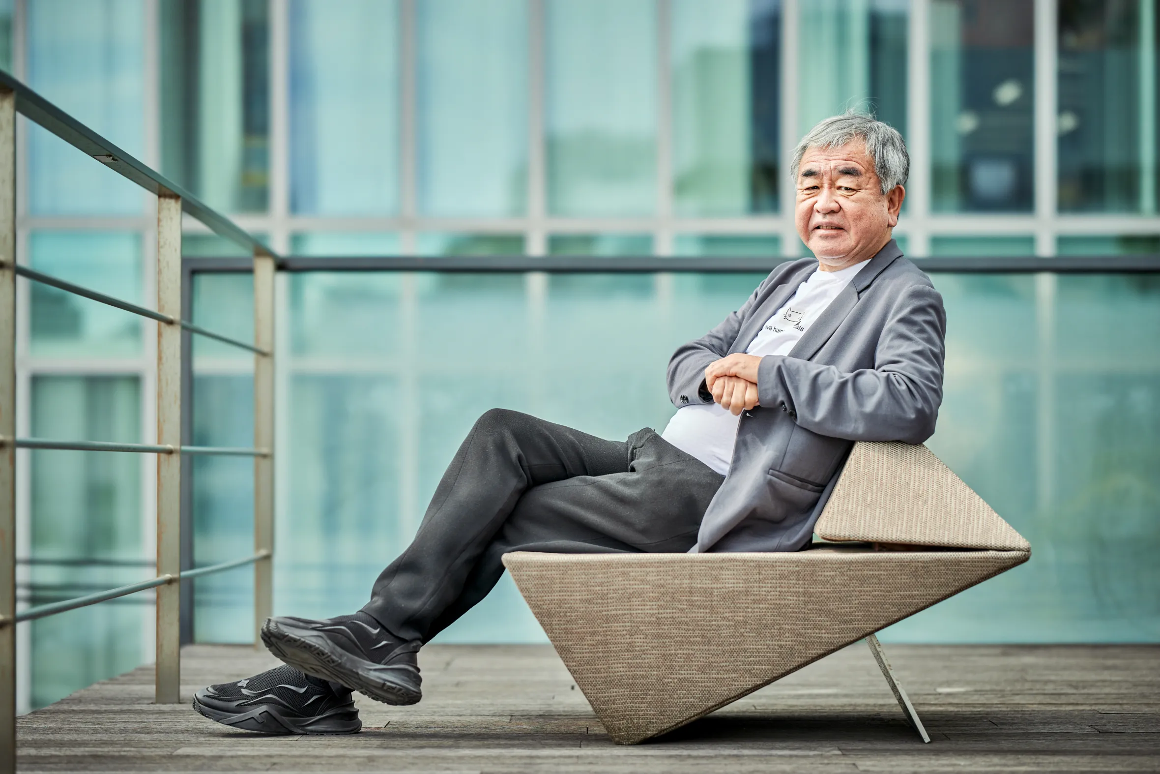 Architect Kengo Kuma seated on a modern chair with folded hands.