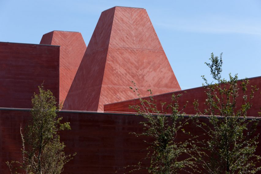 Close-up of the museum's pyramidal towers showing red pigmented concrete with herringbone-patterned formwork