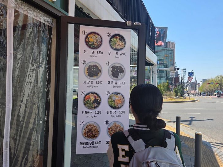 A university student examines a menu outside a restaurant in Seodaemun District, Seoul, April 7. Korea Times photo by Na Min-seo