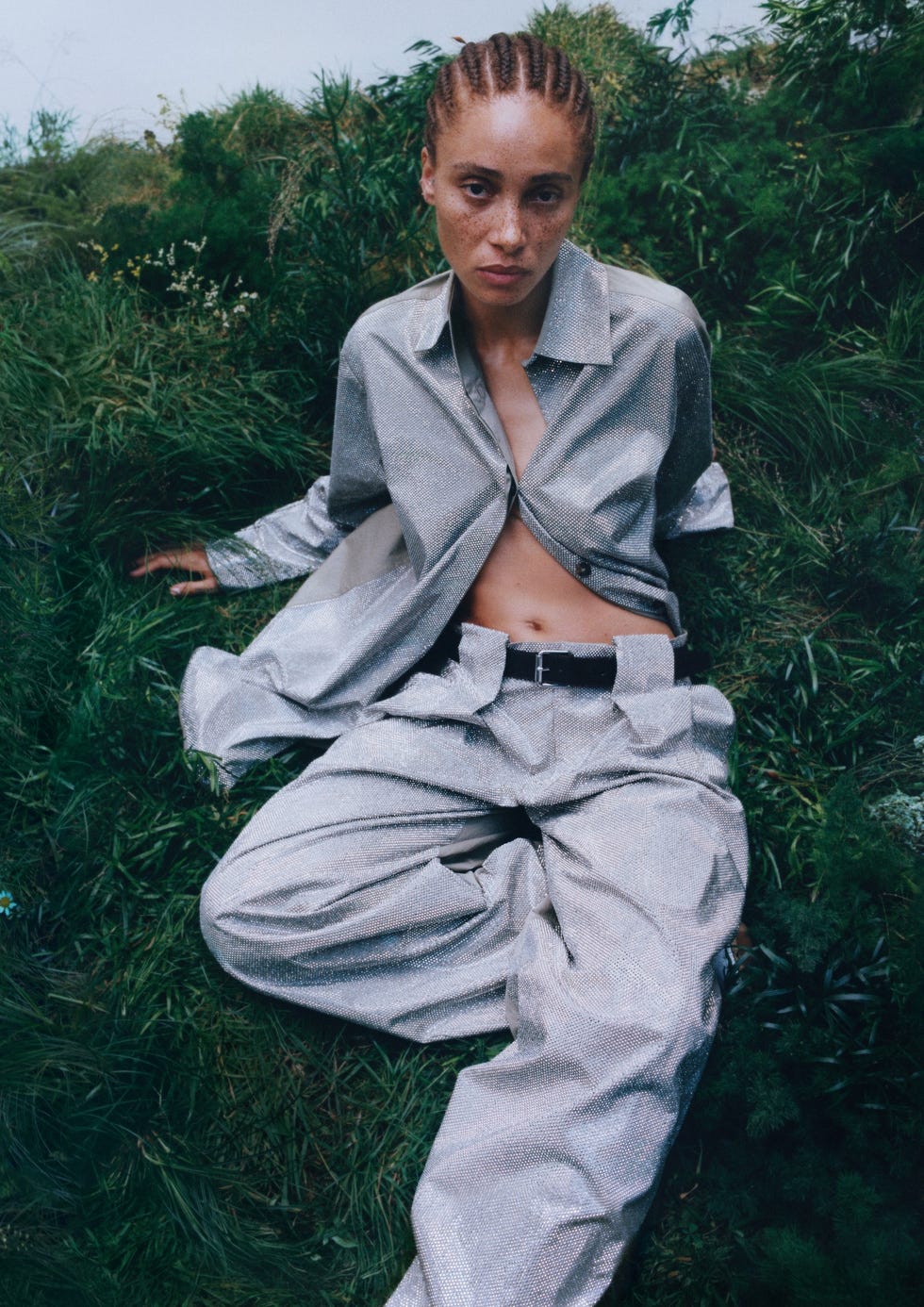 person wearing a metallic outfit seated in lush greenery
