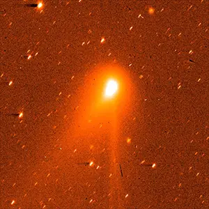 GIF of Comet 3I/Atlas switching between orange and blue views of a bright, glowing object sitting slightly above the center of the image, with a soft, teardrop-shaped head and a long, faint tail streaming downward. The orange view also has a tail pointing to the lower left. Credit: ESA