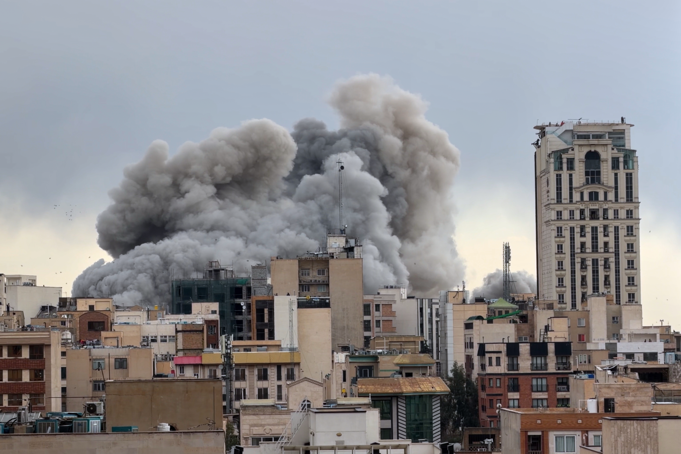 A large plume of smoke rises above buildings in Tehran, Iran, after a strike.