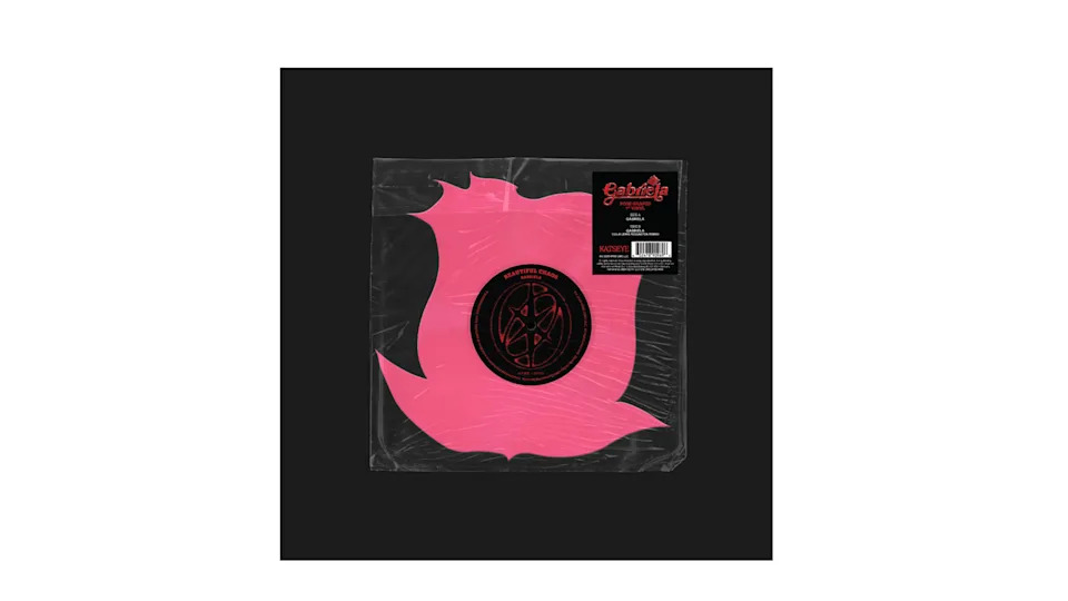 A pink, flame-shaped vinyl record in a clear sleeve with a black and red label.