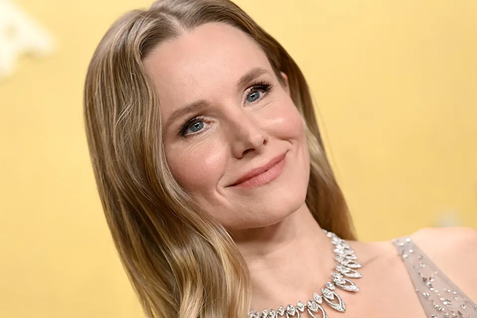 Person smiling at a formal event, wearing an elegant dress with a sparkling necklace