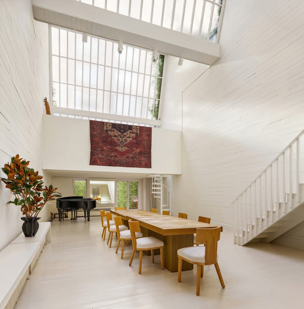 Modern dining area with wooden table and piano in a bright interior.