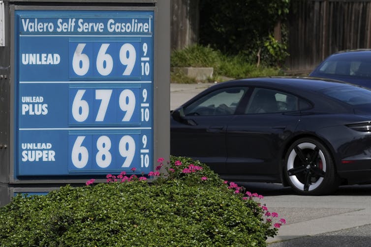 A car drives past at gasoline price board.