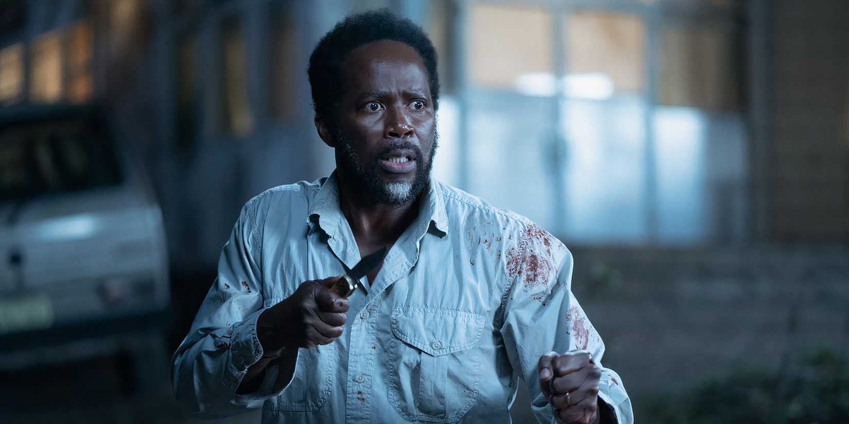 Harold Perrineau as Boyd stands ready to fight with a knife, wearing a bloody shirt in From Season 2.