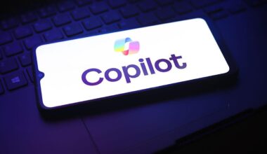 A phone on a laptop shows the Copilot logo on a white screen.
