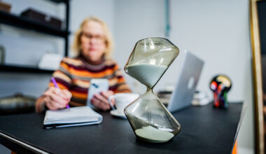 An hourglass beside a woman making notes