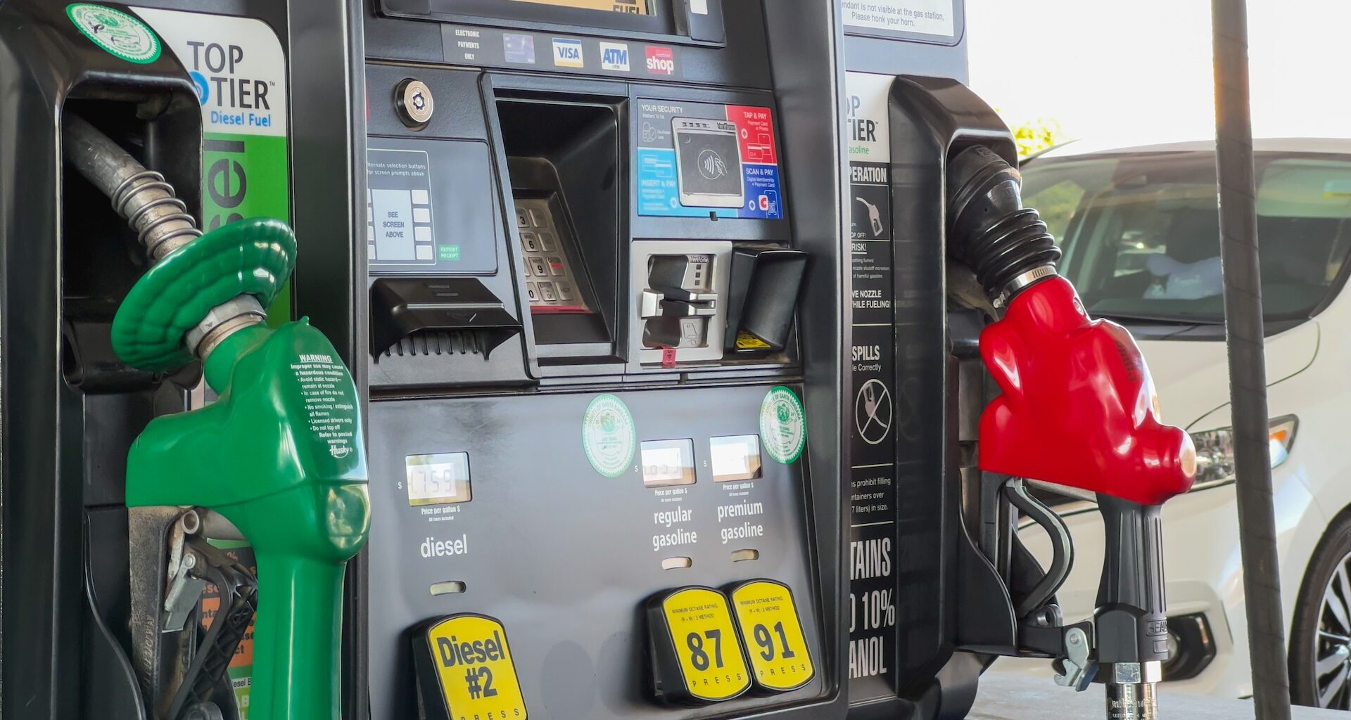 A fuel pump with green diesel and red gasoline nozzles at a gas station.