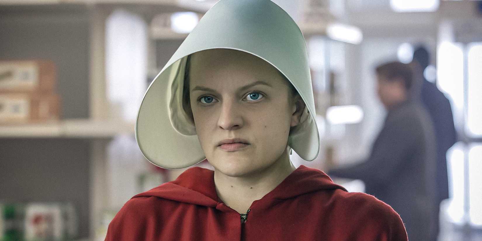 Elisabeth Moss as June Osborne in The Handmaid's Tale, wearing her red robe and white cap and sporting an angry look on her face