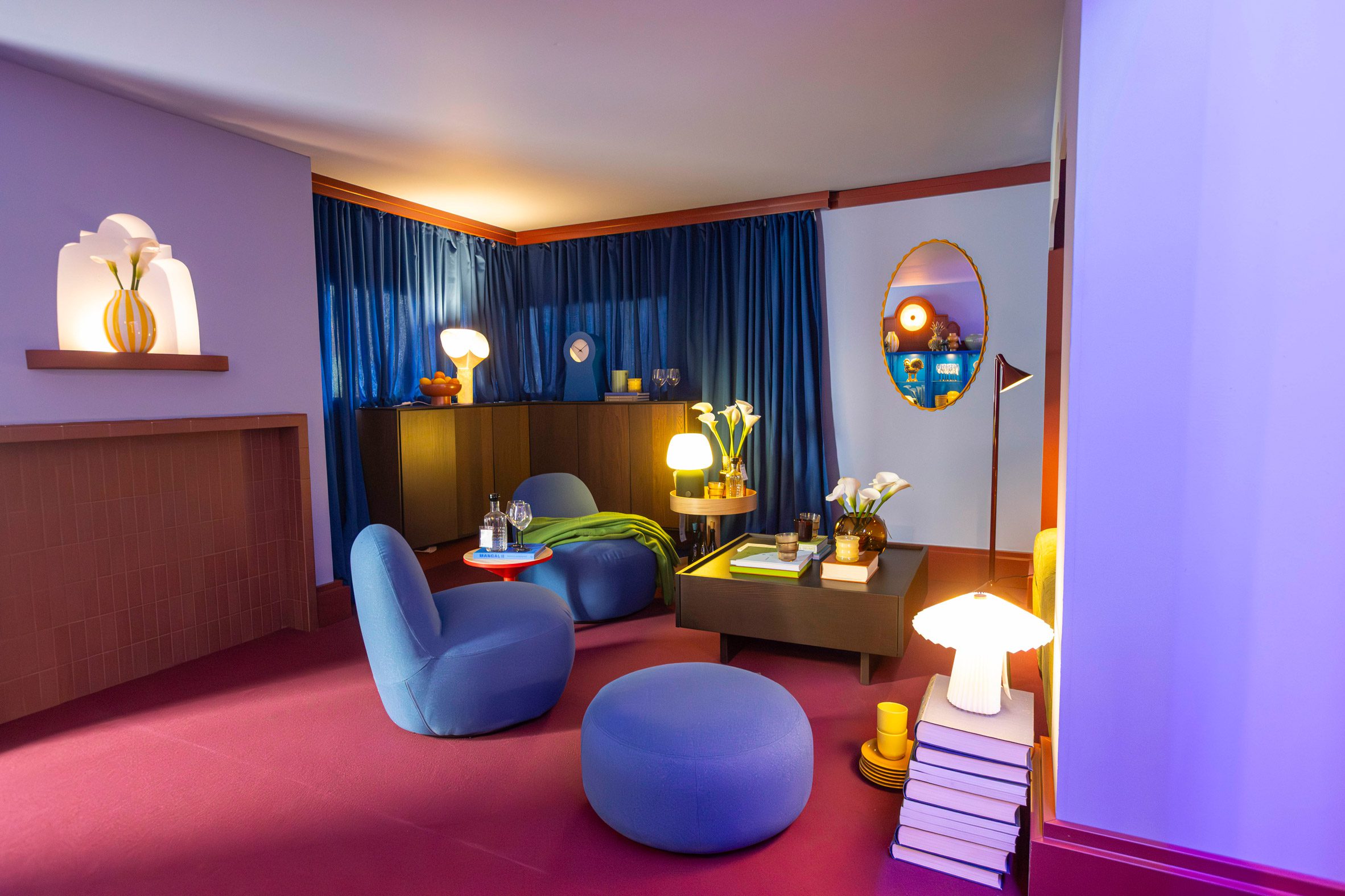 A living room set with blue seating, red flooring and warm lighting featured in IKEA’s Food for Thought exhibition in Milan