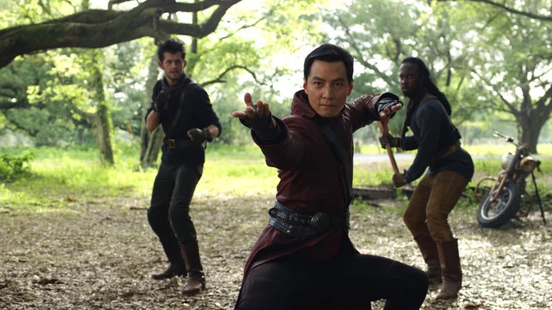 Sunny in an outdoors martial arts pose with two men behind him