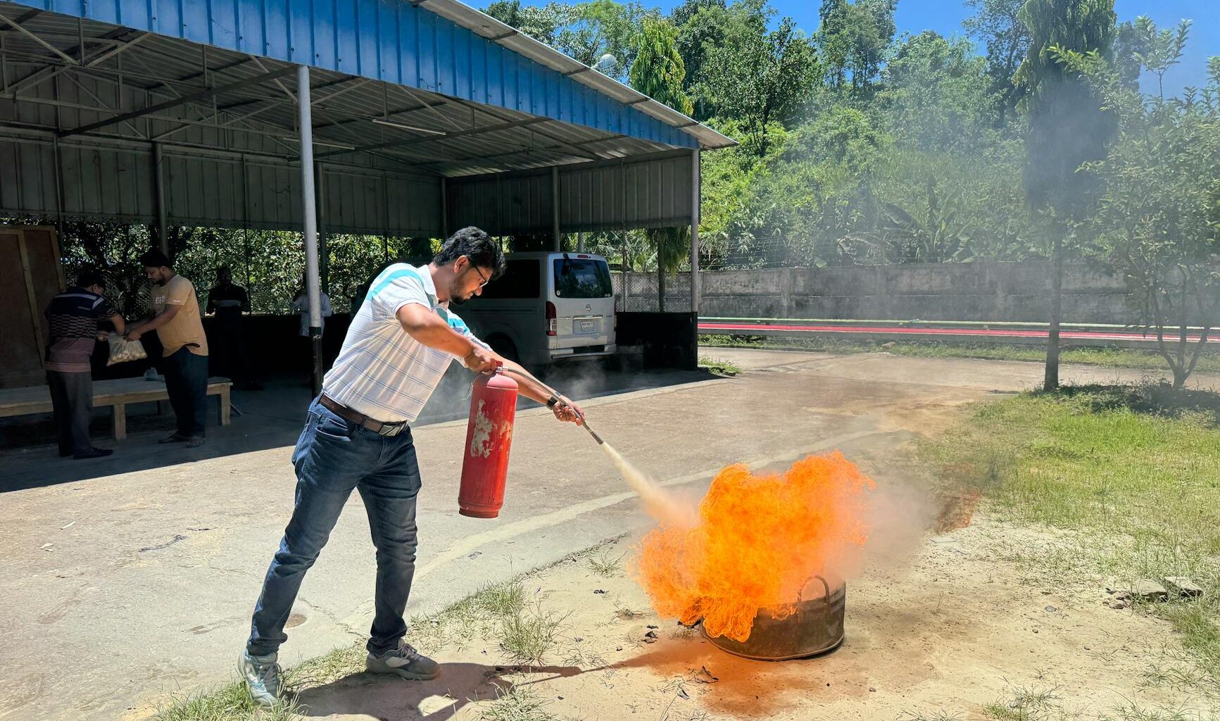 A man uses a fire extinguisher to put out a controlled fire during an outdoor safety training session.