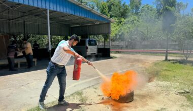 A man uses a fire extinguisher to put out a controlled fire during an outdoor safety training session.