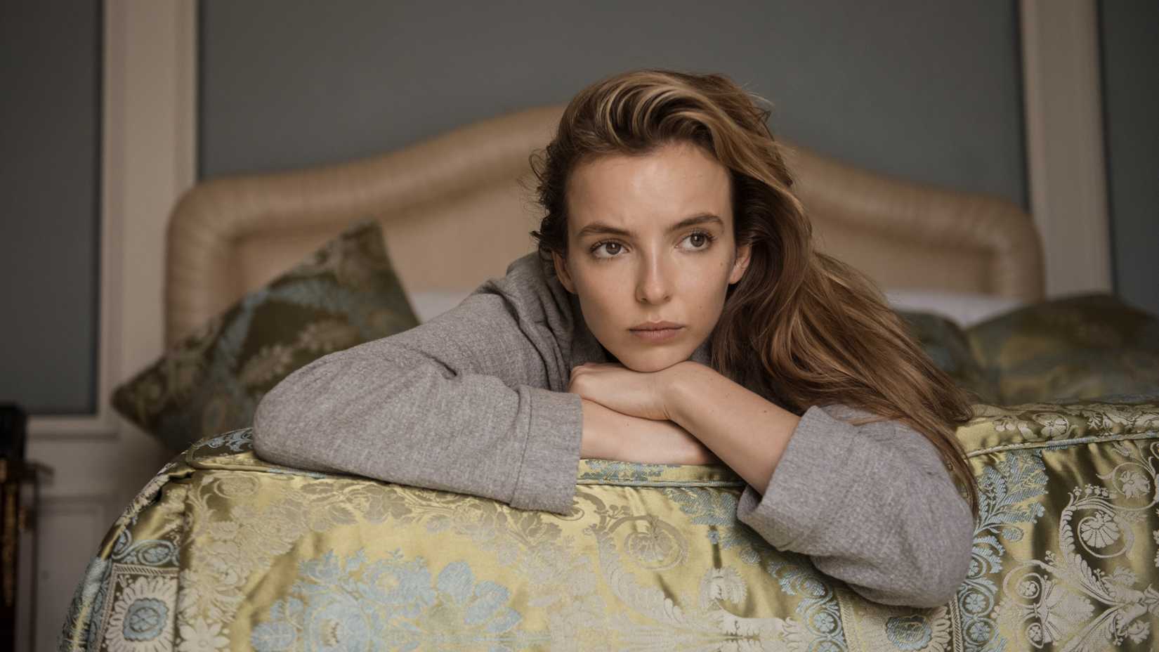 Jodie Comer as Villanelle lying down on a bed in thought in Killing Eve season 2