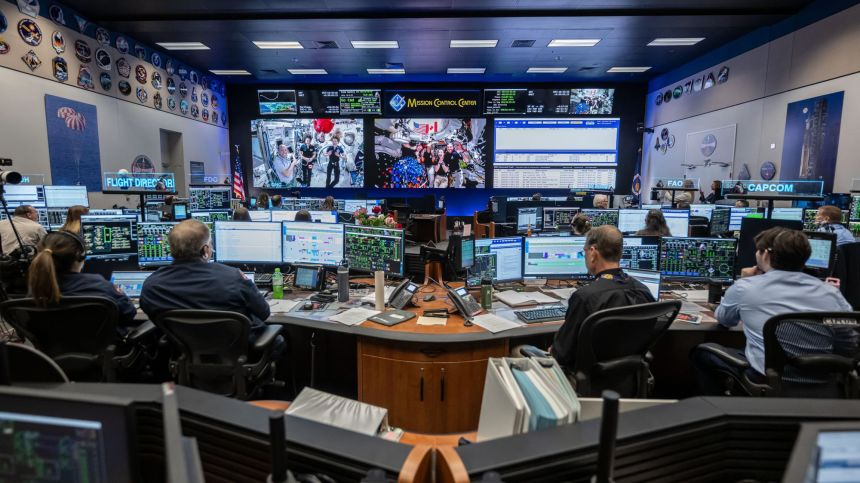 (From left) Members of the International Space Station and Artemis II crews are seen on the screens inside the ISS flight control room in the Mission Control Center at NASA's Johnson Space Center in Houston. The two crews connected in a 15-minute ship-to-ship call on April 7.