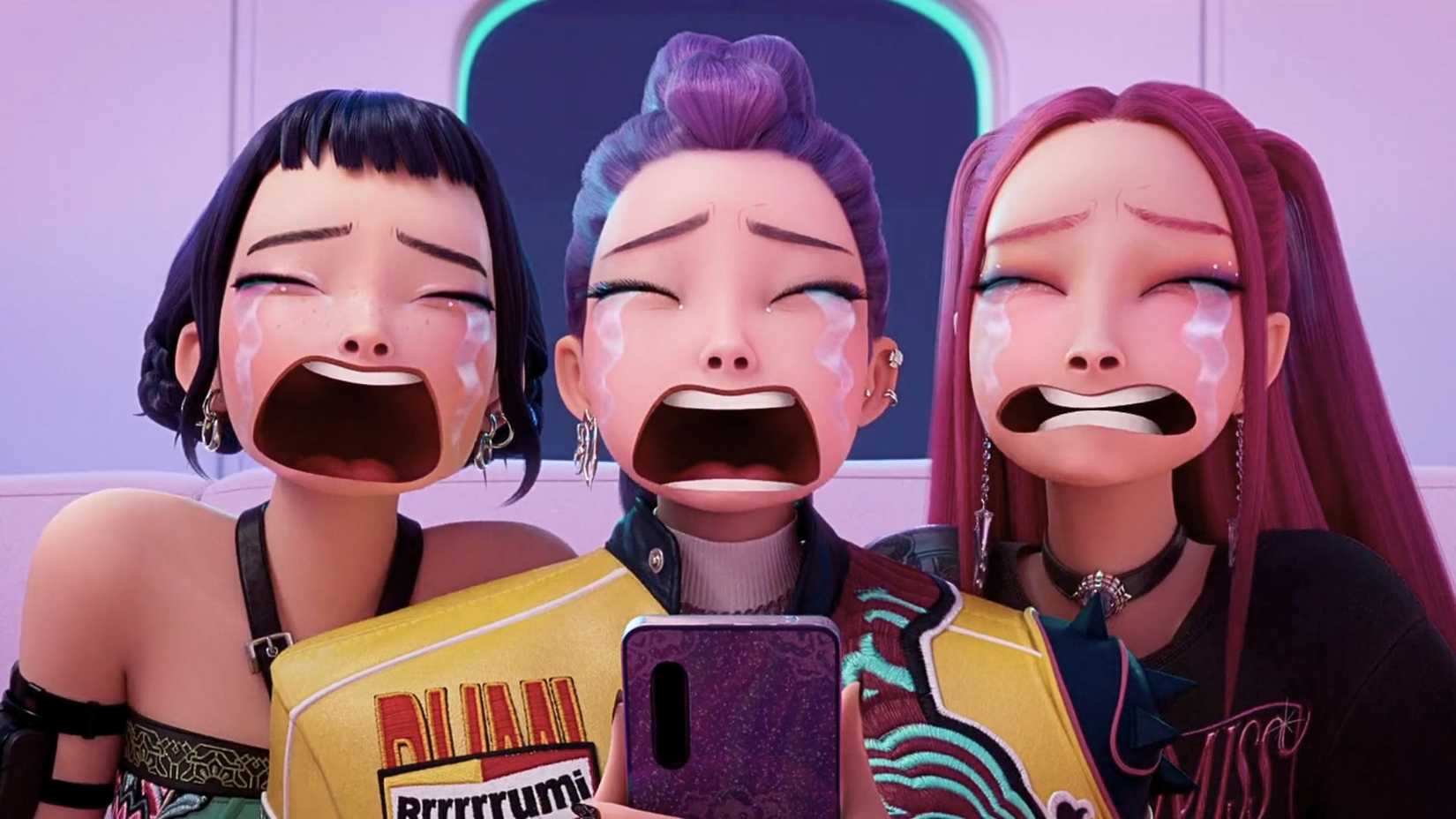 A screenshot from KPop Demon Hunters. It portrays Rumi, Zoe and Mira looking at a phone with tears running down their face.