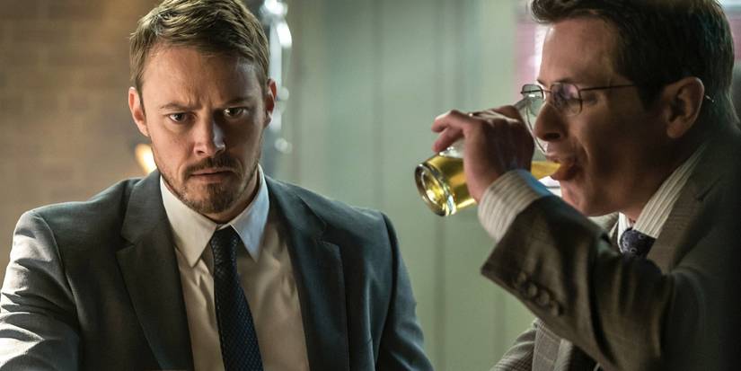 Michael Dorman looking confused while someone a man next to him drink a beer in Patriot