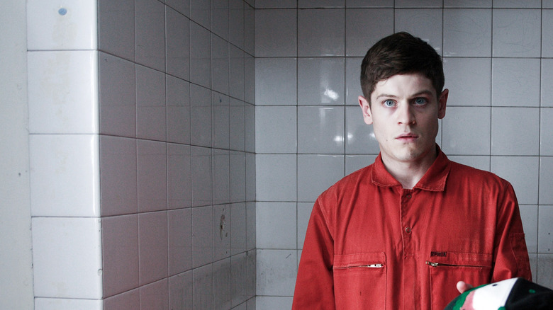 Simon Bellamy stands in a bathroom in a community service jumper
