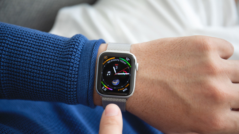 A seated man in a blue shirt with a bright Apple Watch display