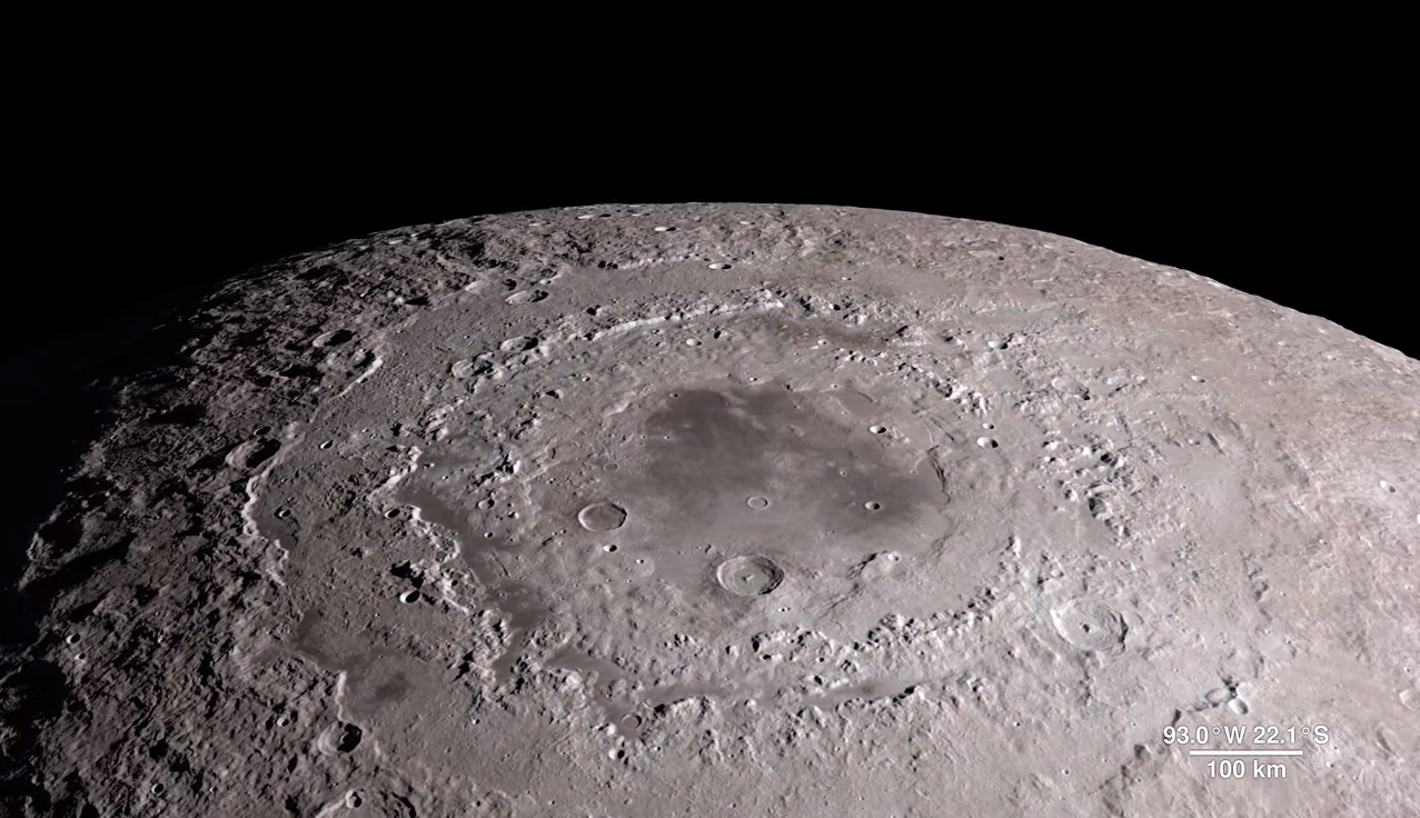 A view of a cratered lunar surface with a darker section in the center.