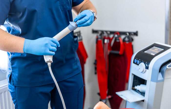 Surgical staff in blue scrubs and gloves preparing medical equipment for patients under sedation in a clinical setting.