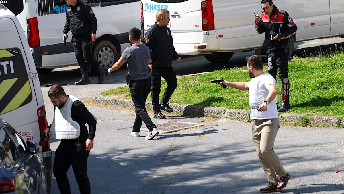 Plainclothes police officer holding a gun in Istanbul street.