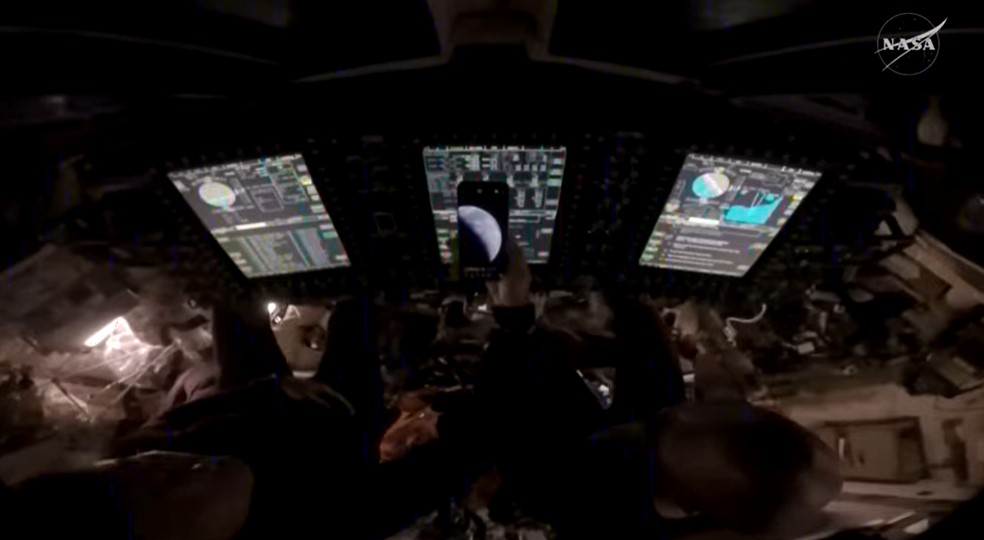 NASA astronauts Reid Wiseman and Victor Glover show a photo of Earth taken just moments after the Orion spacecraft ignited its thrusters for a final burn for 8 seconds, pushing Artemis II toward Earth. Credit: NASA