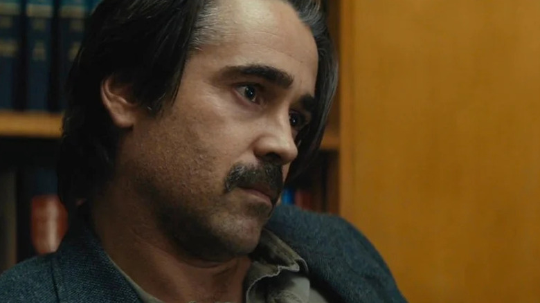 Ray Velcoro (Colin Farrell) wears a grey suit, his head cocked to the side with a serious expression in True Detective