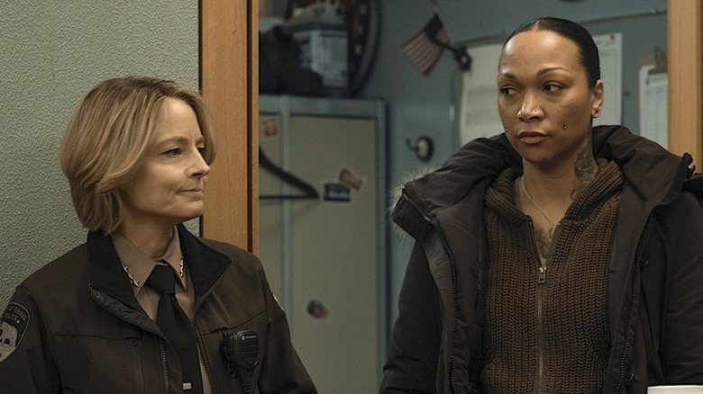Jodie Foster (Detective Liz Danvers) and Kali Reis (Detective Evangeline Navarro) in police uniforms and heavy jackets, Foster with a closed-mouth smile, and Reis side-eyeing her in True Detective