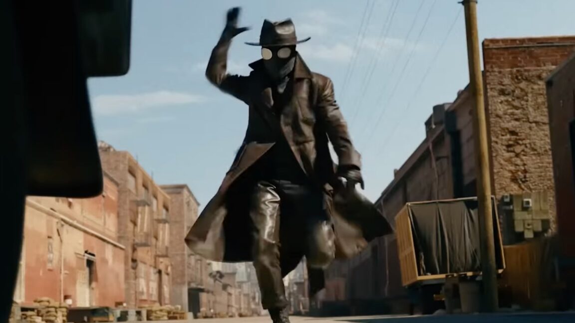 man in 1940s trench coat and black mask with hat running down a street ready to attack