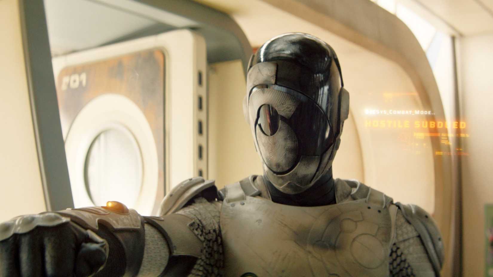 Alexander Skarsgard as Murderbot with its helmet down and text reading "Hostile Subdued" in Murderbot season 1