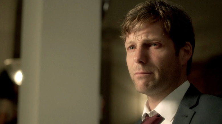 Jamie Bamber as Kev wearing suit with tears in his eyes in The Smoke