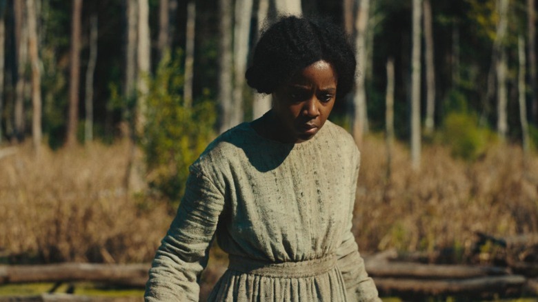 Cora Randall standing in the woods and looking down on The Underground Railroad S1E1