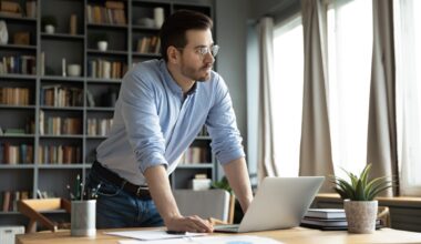 An investor leans against a desk and looks pensively out a window.