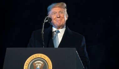 A smiling Donald Trump delivering remarks from behind the presidential podium.