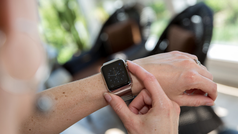 Person using an Apple Watch with a car in the background