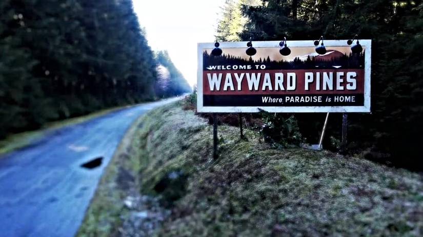 "Welcome to Wayward Pines" sign on the side of a road in from the Wayward Pines opening credits