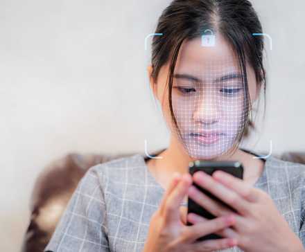 Woman using smartphone with face scanning technology like Face ID