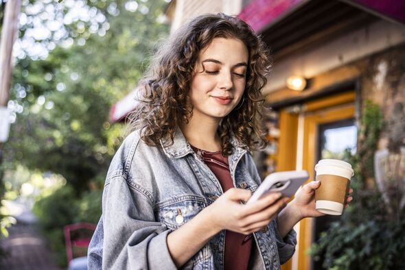 Young woman using smartphone in front of cafe