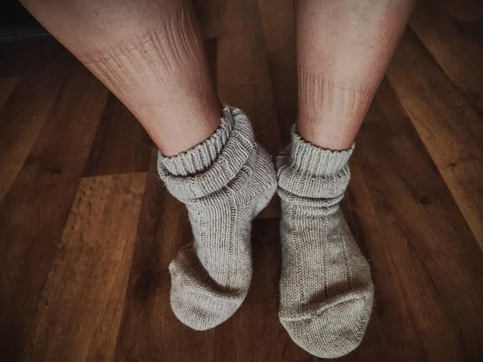 Close-up of feet wearing wool socks showing sock indentations on the skin above the ankles