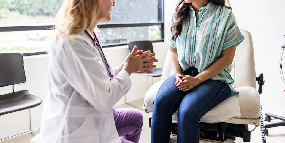 Doctor consulting with a patient seated on an exam table in a medical office, both engaged in conversation
