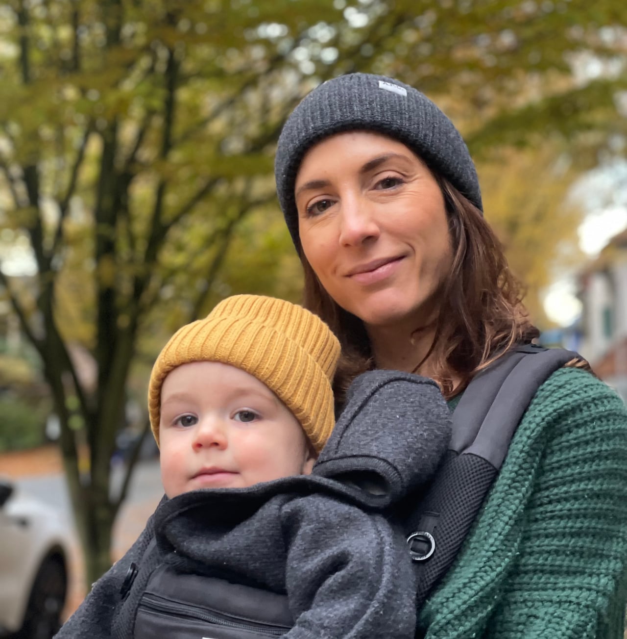 A woman holds a baby in a carrier.