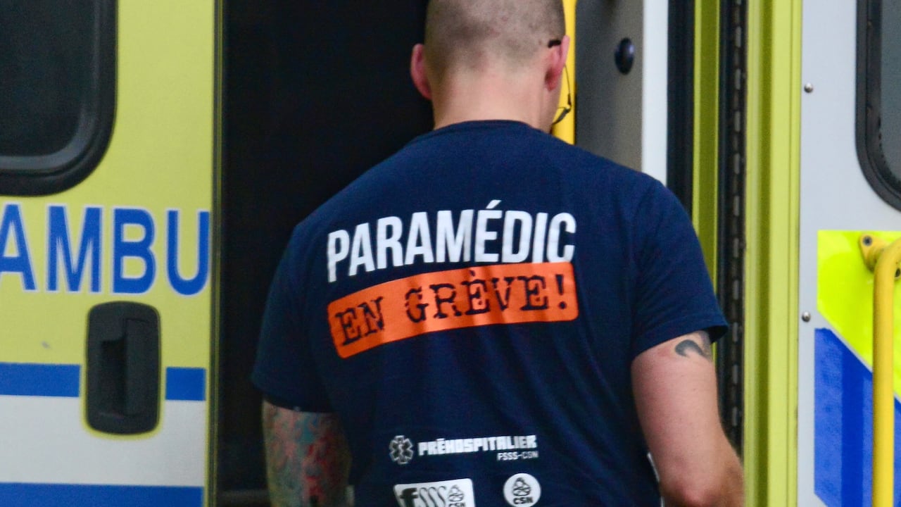 Man standing in front of yellow ambulance with back facing showing T shirt that says paramedic en greve